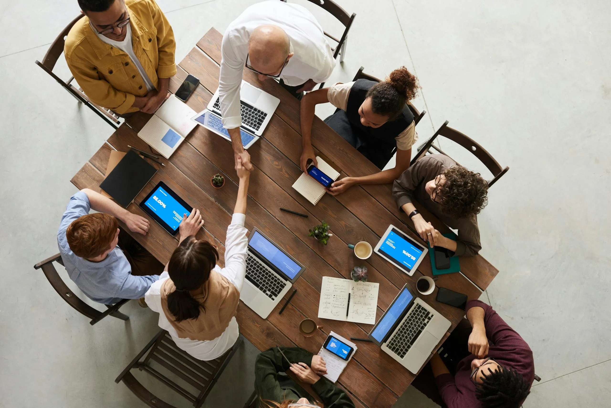 A team collaborating around a table with laptops and tablets.